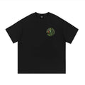 Black oversized streetwear t-shirt with green illustrated figure and patterned circle graphic