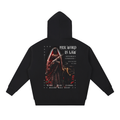 A black pullover hoodie shown from the back, featuring a large graphic print of a hooded figure holding a sword with text including 'HER WORD IS LAW' and 'Sovereign Command'.