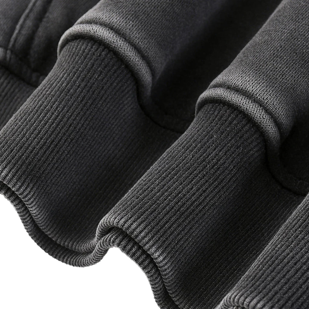 Close-up of a dark gray sweater with ribbed cuffs and hem on a white background